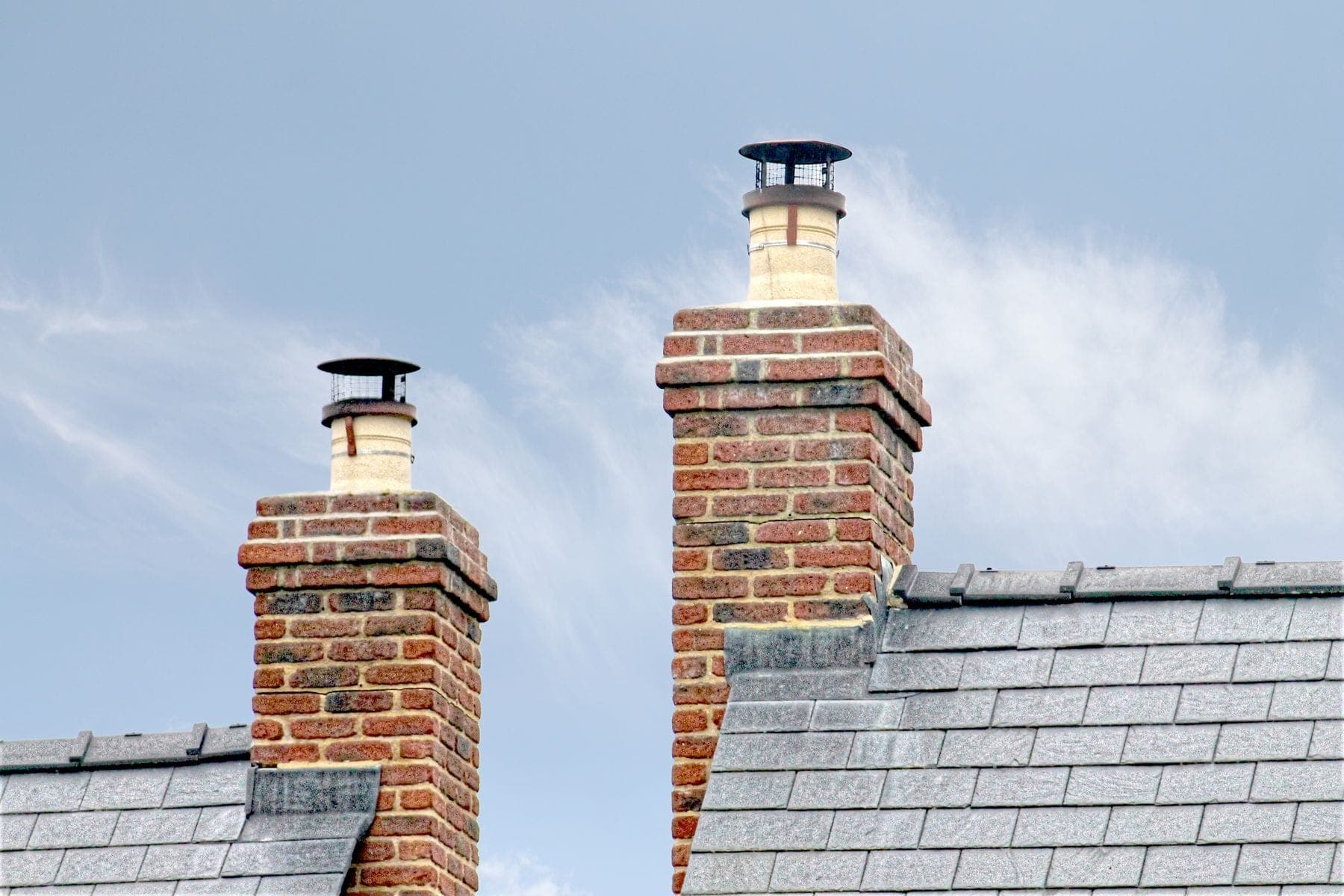 Brick chimney stacks on a slate roof with lead flashing at the base
