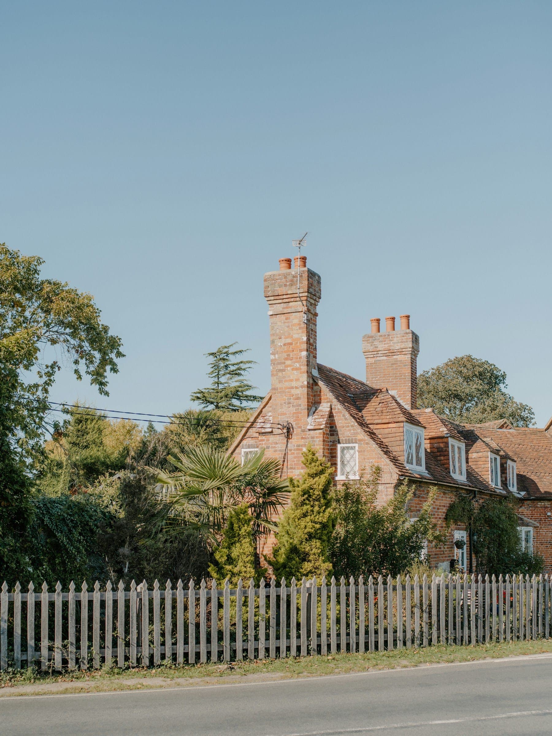 A detached brick house with a tiled roof and tall chimneys