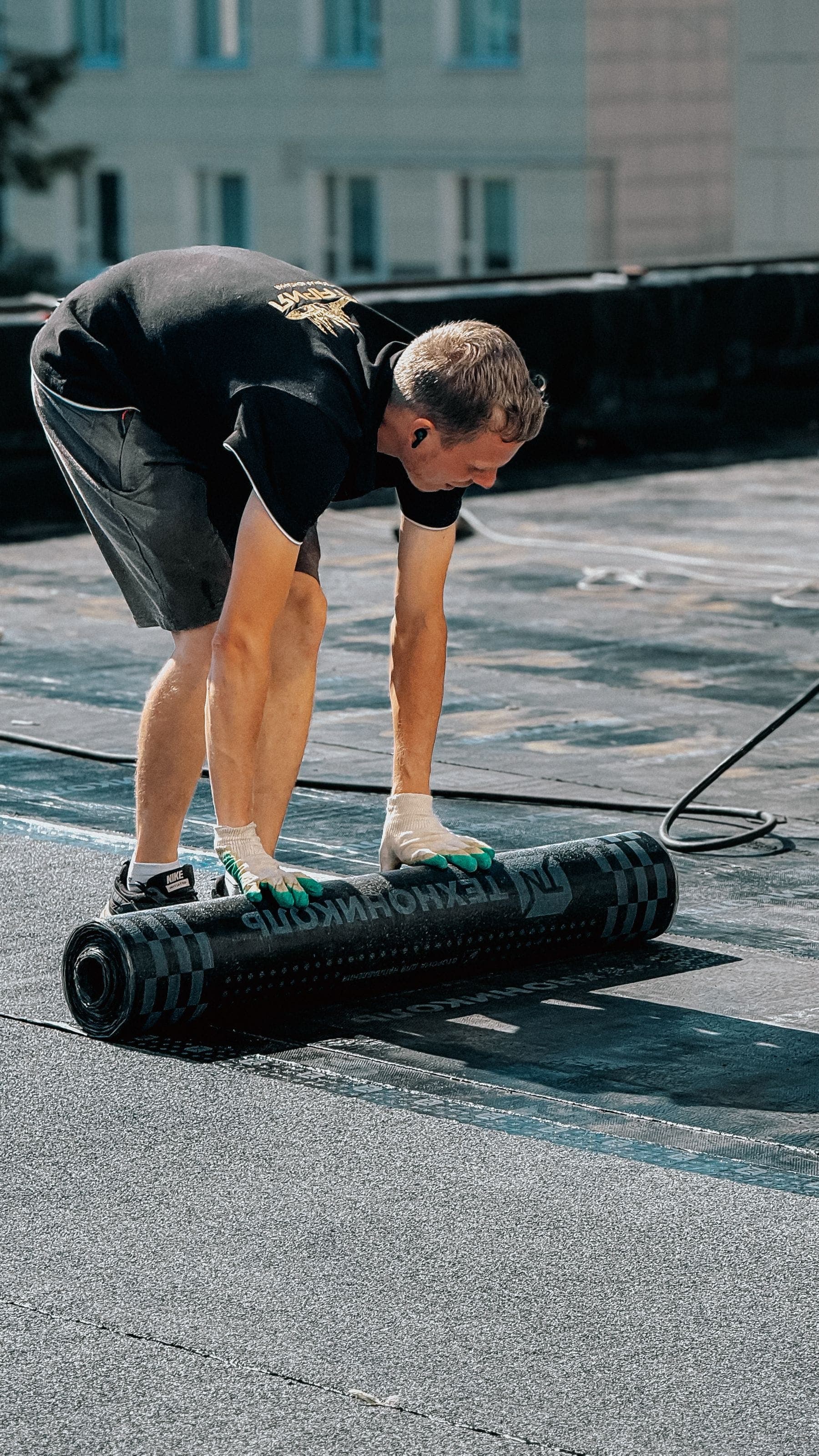 A roofer unrolling felt on a flat roof