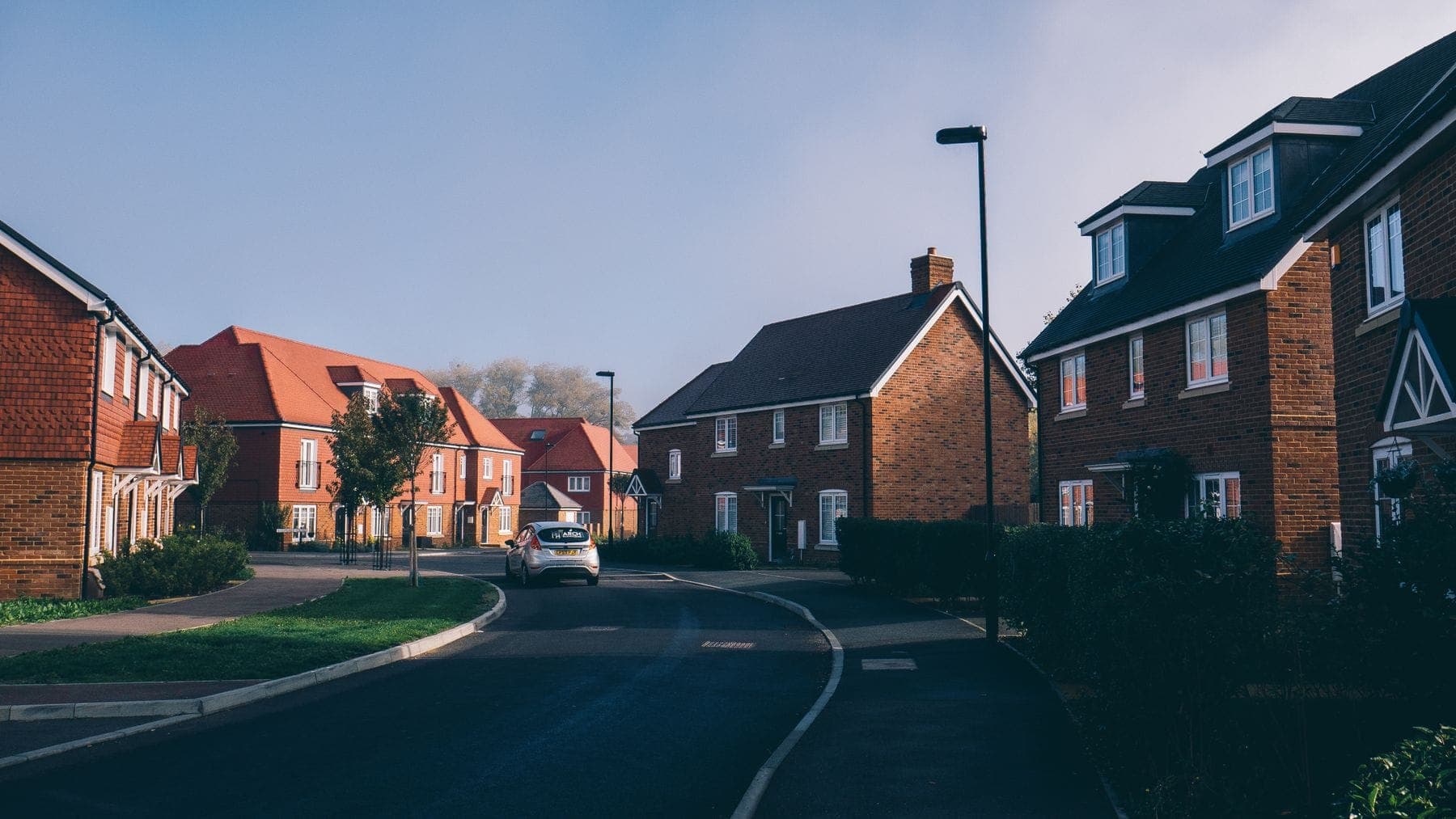 A suburban street of brick semi-detached houses with tiled roofs
